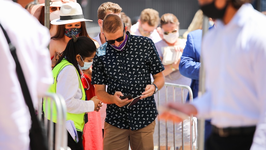 A man wearing a mask shows a security guard his phone.