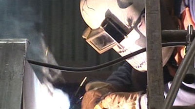 A person in a mask welds.