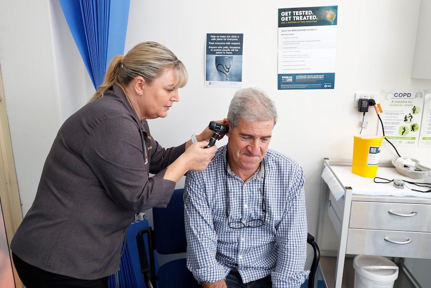 a woman checking a man's ear