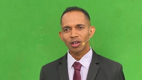 A man in front of a green screen talking