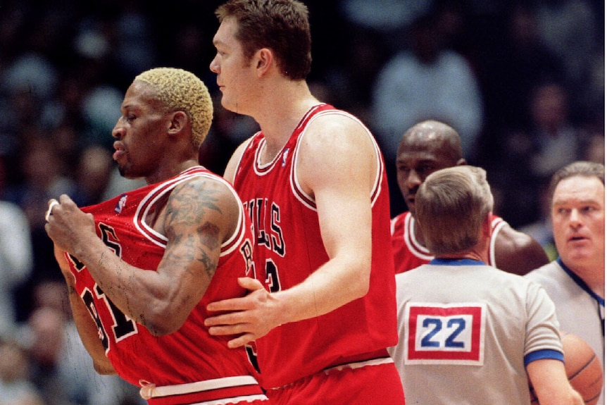 Chicago bulls player luc longley escorts dennis rodman off basketball court