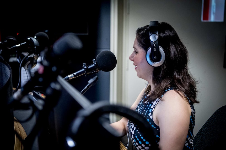 Nas Campanella in a radio studio, wearing headphones and speaking into a mic.