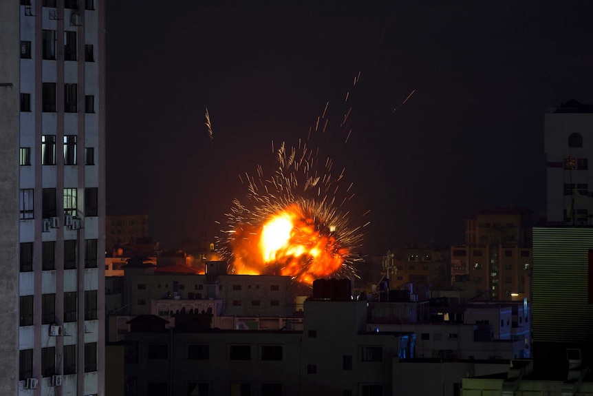 A ball of fire hits a building in a city landscape, with sparks lighting up the night sky.