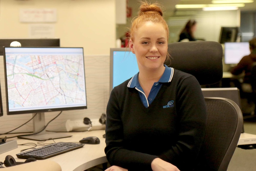 A woman sitting at work next to a computer smiling at the camera.