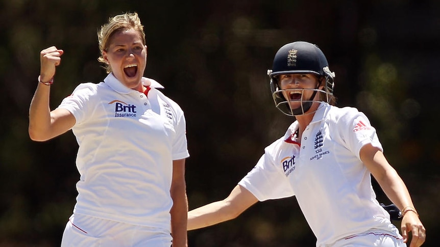 Katherine Brunt celebrates a wicket by raising her first in the air, her teammate is next to her smiling.