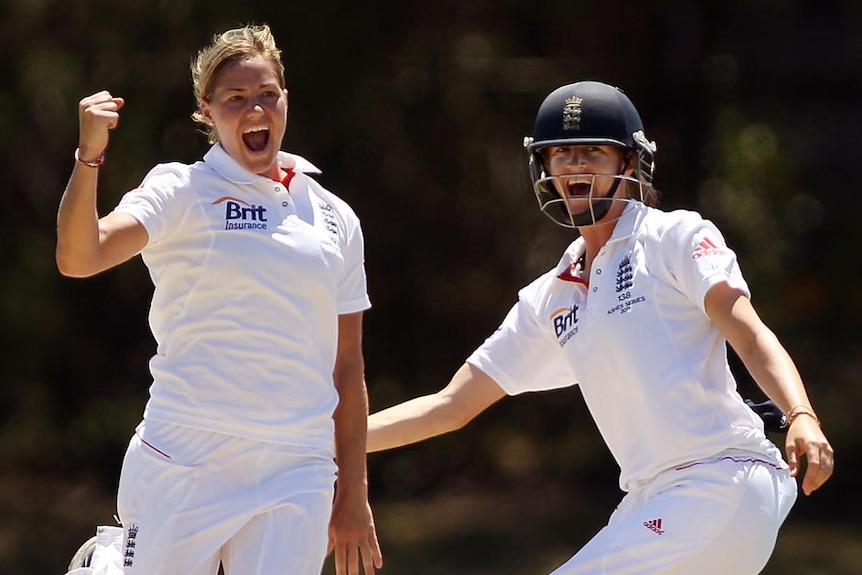 Katherine Brunt celebrates a wicket by raising her first in the air, her teammate is next to her smiling.