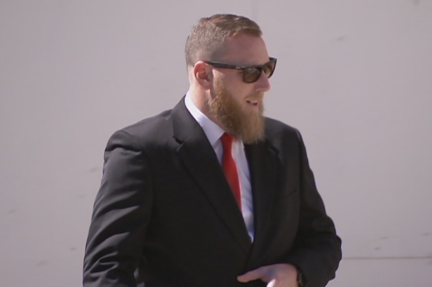 Timothy Stewart McLeod, dressed in a suit with a red tie in front of the ACT Supreme Court.