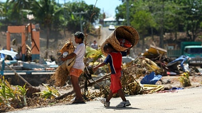 Samoan children carry salvaged bedding (Getty Images)