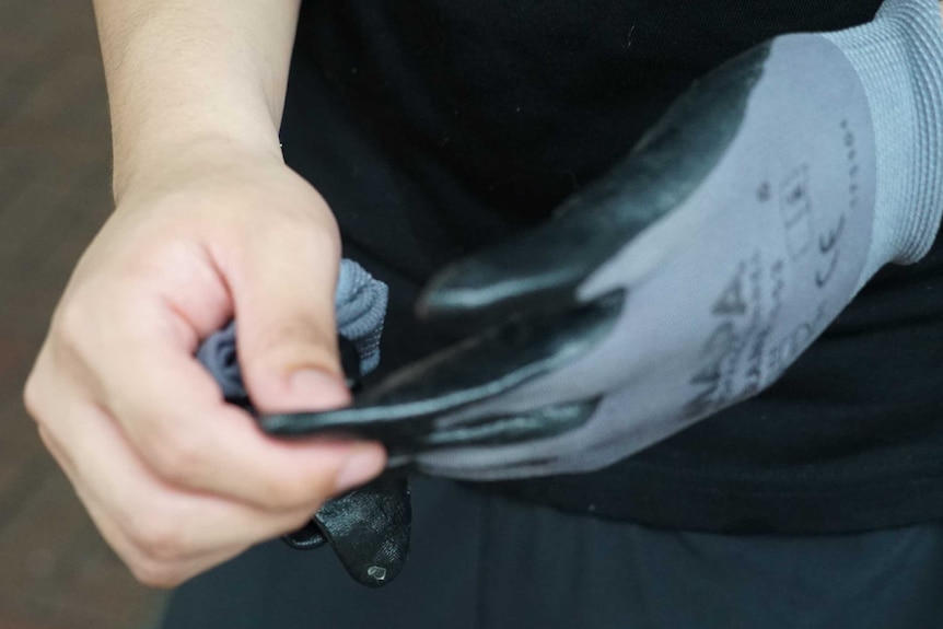 A close-up shot of a man's hands as he pulls off gloves