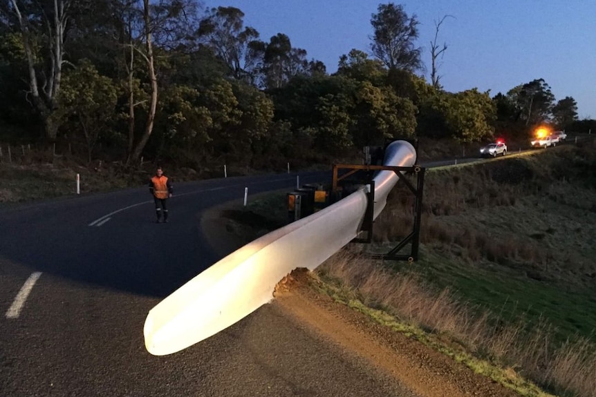 A wind turbine wing left on the road after a truck rollover.