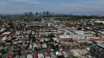 Aerial view of houses in the foreground with a city skyline in the background