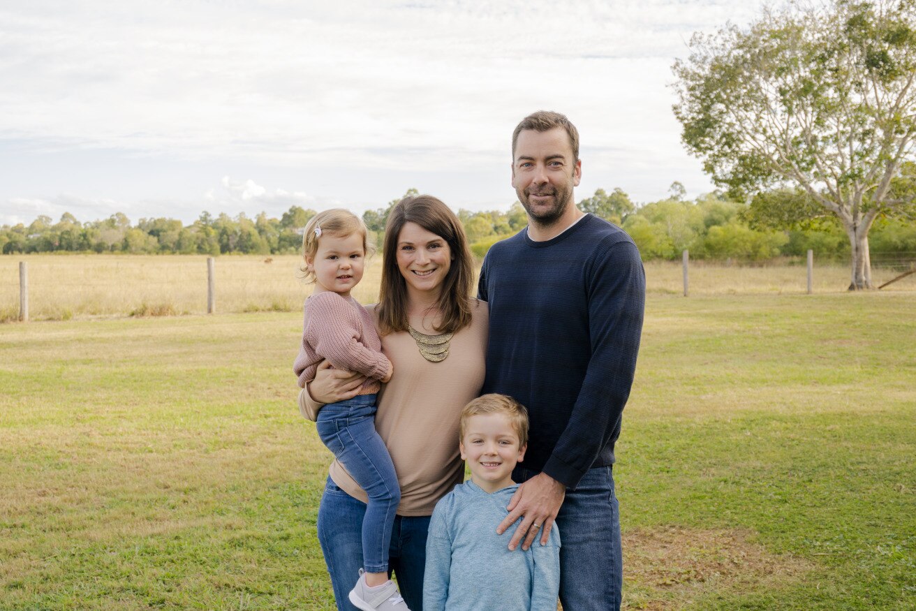 Husband and wife standing with their two children outside. 