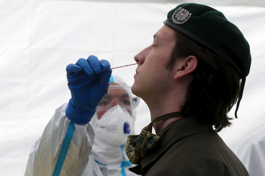 A soldier is tested for coronavirus with a nasal swab by a health worker