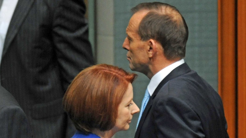 Julia Gillard and Tony Abbott, shot in profile, pass each other in parliament in 2012.