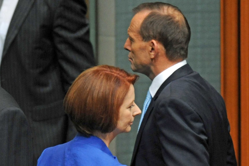 Julia Gillard and Tony Abbott, shot in profile, pass each other in parliament in 2012.