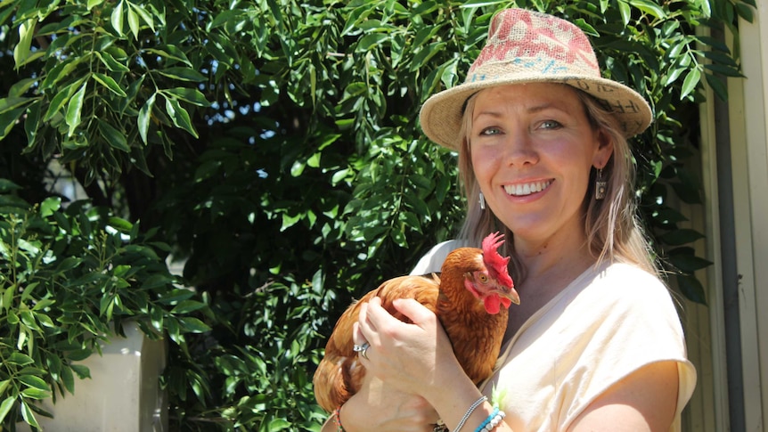 Saturday Night Country host Felicity Urquhart holds a chicken on a farm.