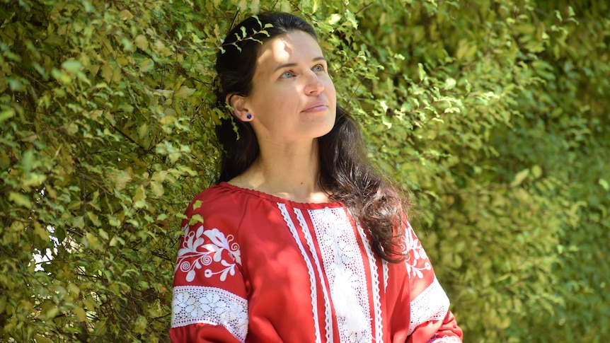 Woman looking away from camera. Dark hair tied back, blue eyes and red and white top