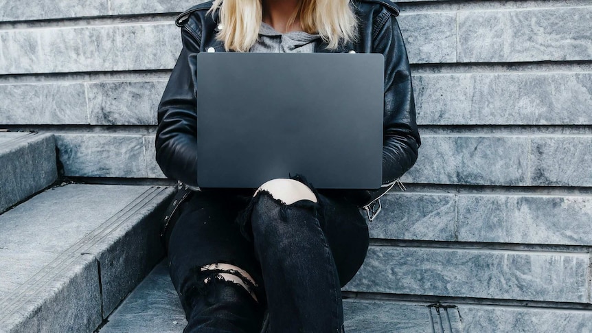 A woman sits with her laptop in her lap during a Reddit article on dating strategies for women.