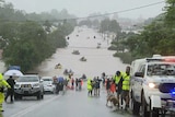 A flooded street with boats and rescue vehicles and people