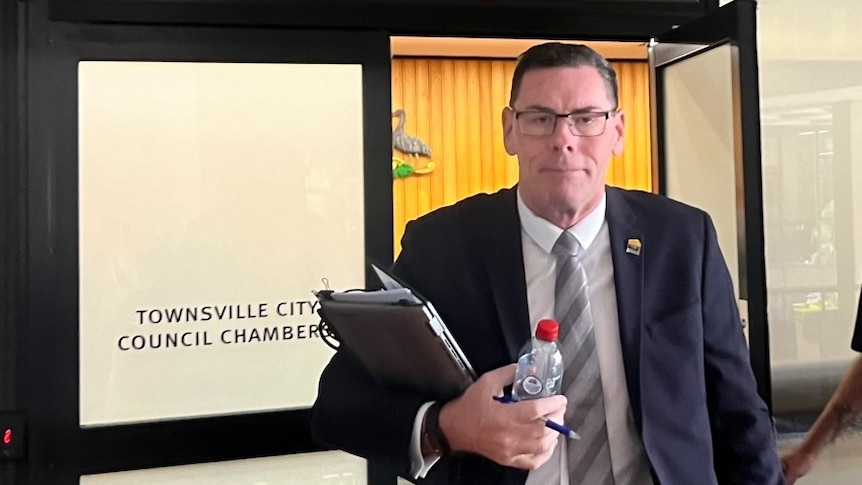 A tall man leaves a room... it says townsville council meeting