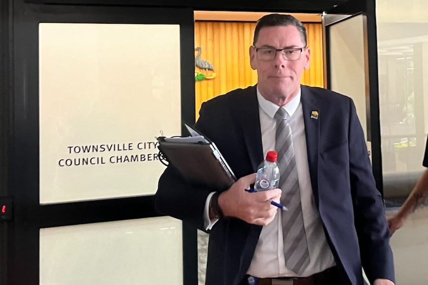 A tall man leaves a room... it says townsville council meeting