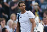 Rafael Nadal trudges off Wimbledon's centre court with a disappointed expression on his face.
