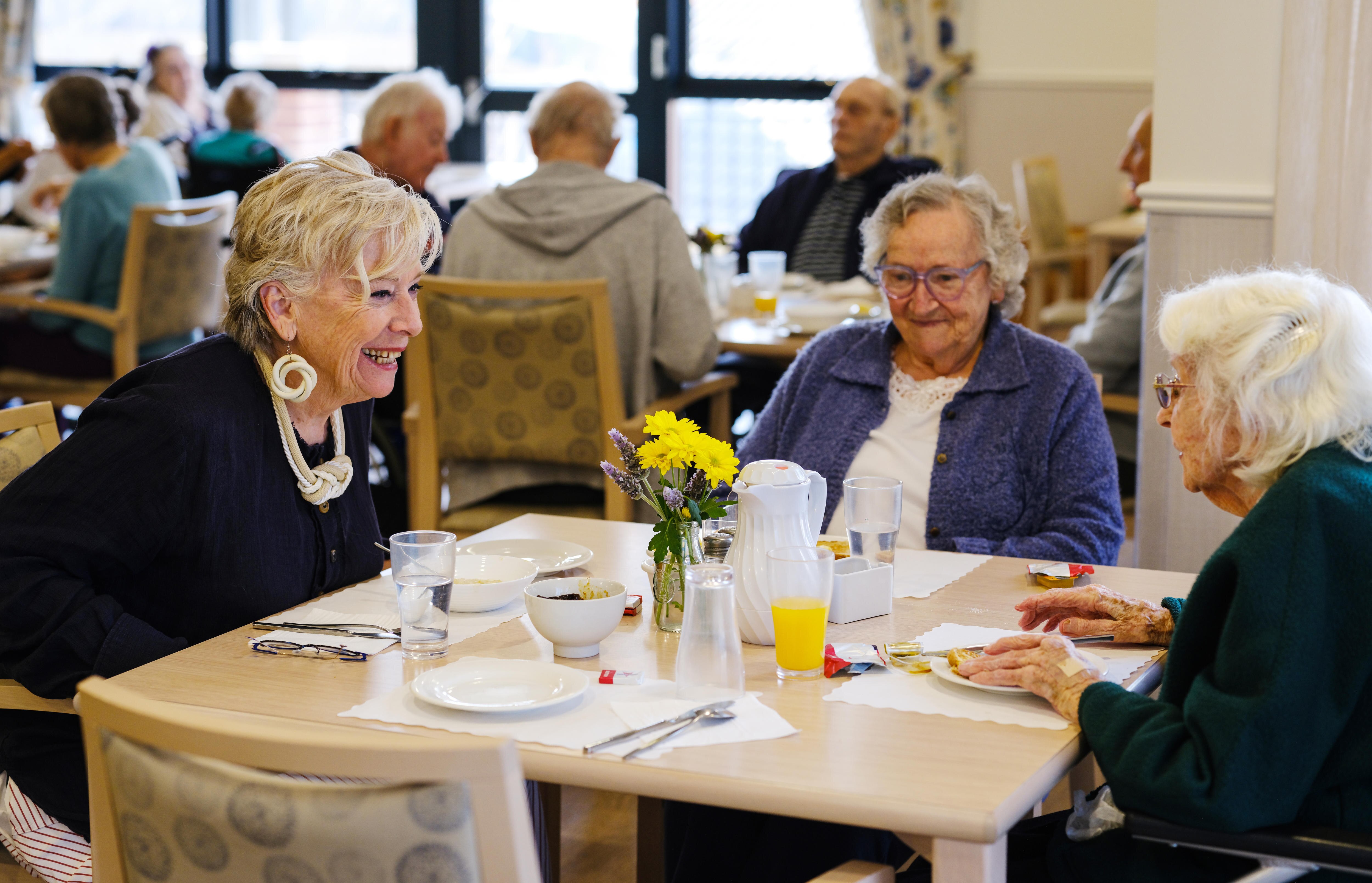 Maggie Beer joins two female residents at the dining hall of an aged care home in Perth.