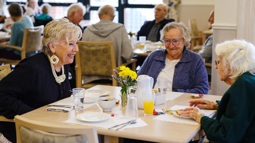 Maggie Beer joins two female residents at the dining hall of an aged care home in Perth.
