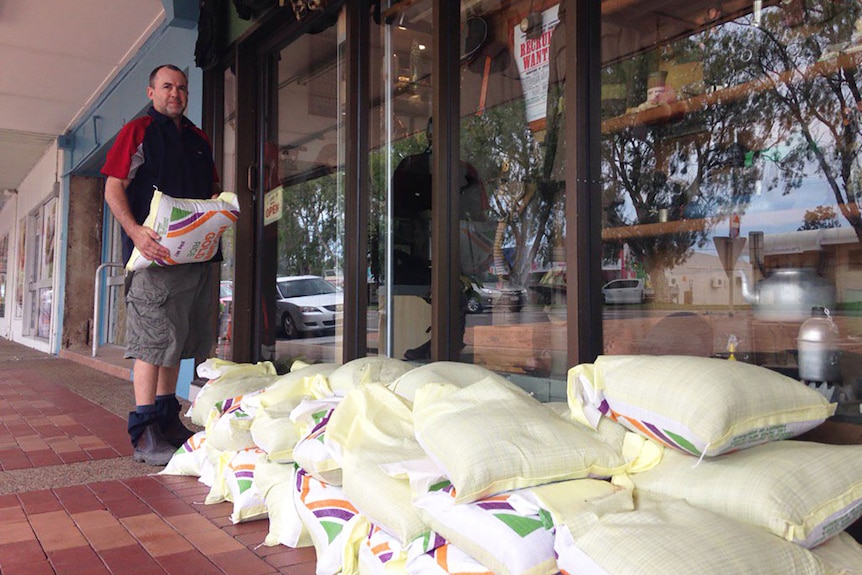 Home Hill shop owner Ken Hall puts sandbags in place in front of his business.