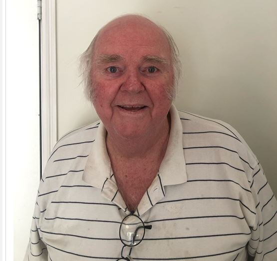 Man with a white collared shirt stars with smiling eyes at camera. 