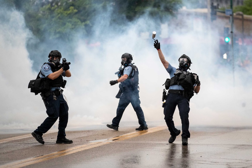 A police officer throws a tear gas canister