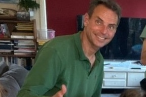 Man in green shirt smiling with thumbs up in house