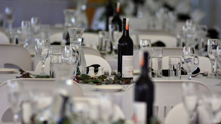 Wine glasses and bottles sit on tables, covered in white tablecloths.