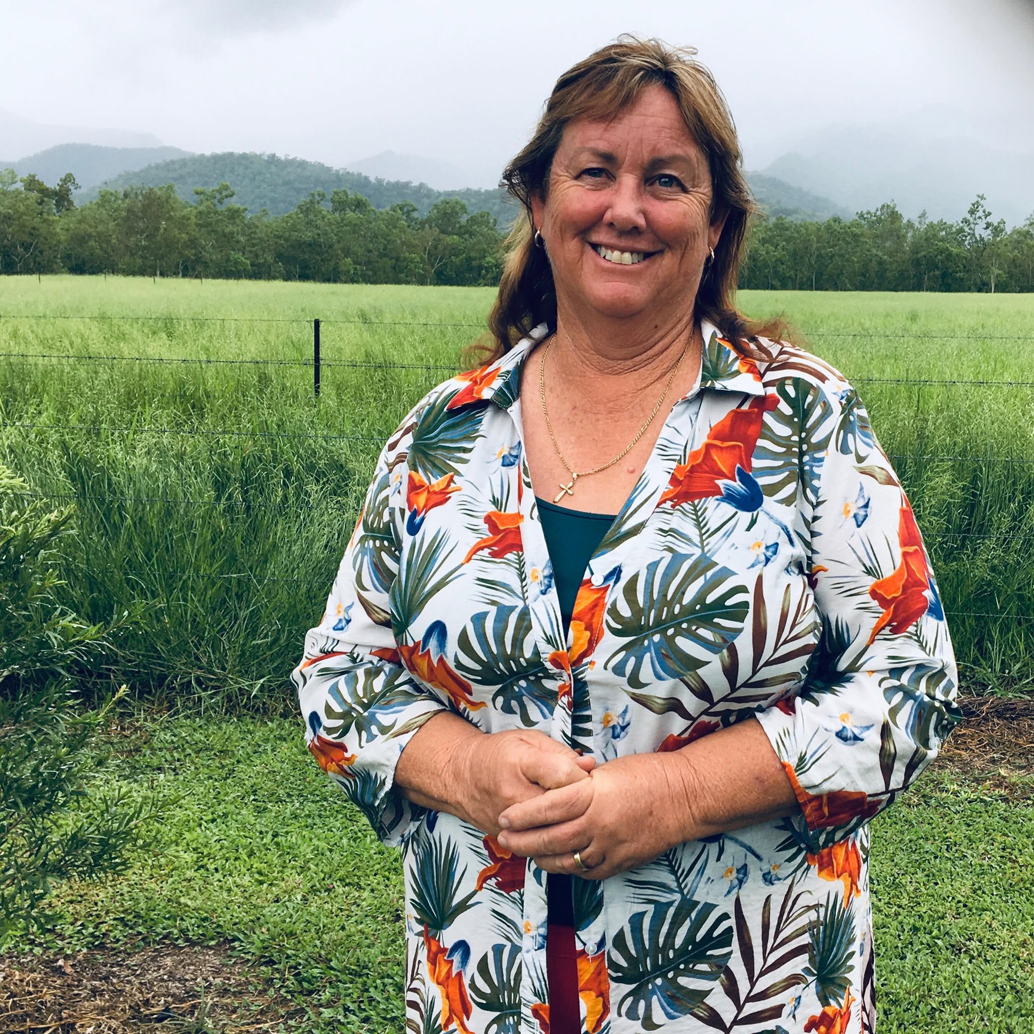 A woman standing in front of a cane farm.