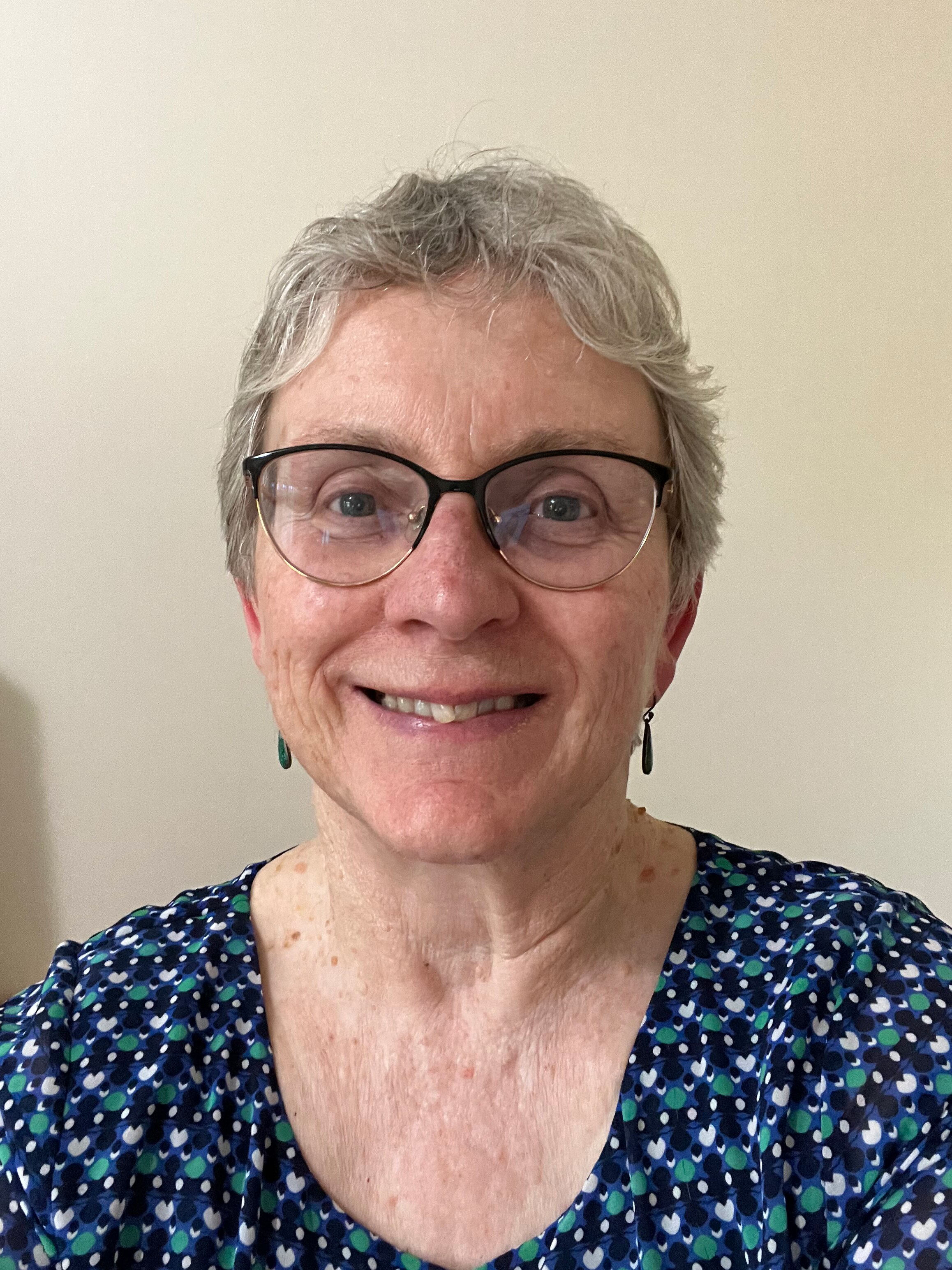 Older woman with grey hair, wearing glasses.