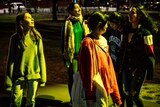 a group of young women stand under lights at an outdoor park