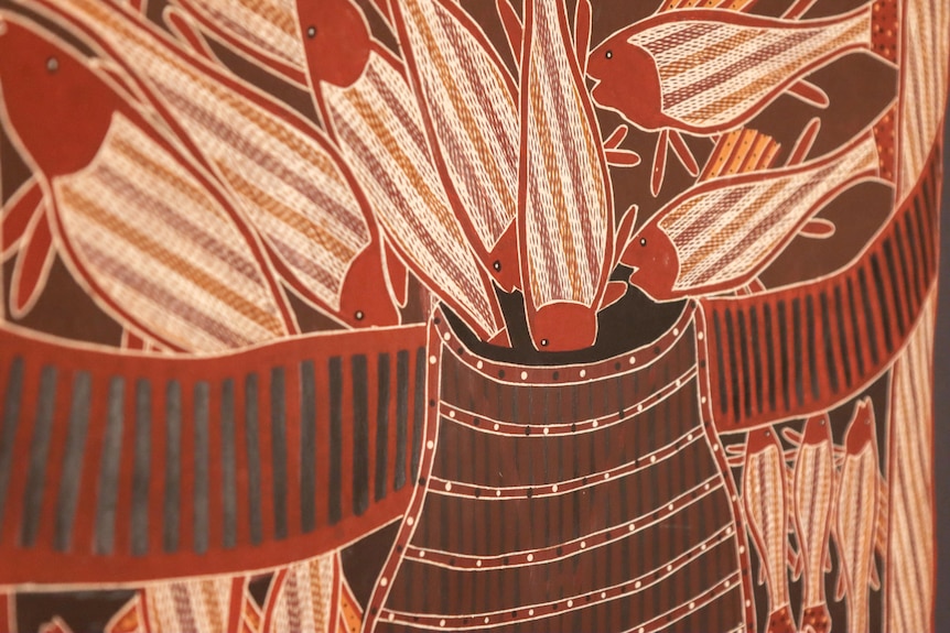 A brown, rust red and white bark painting featuring a traditional Burarra fish trap with fish swimming into it.