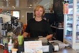 A woman wearing a black tshirt behind a cafe counter