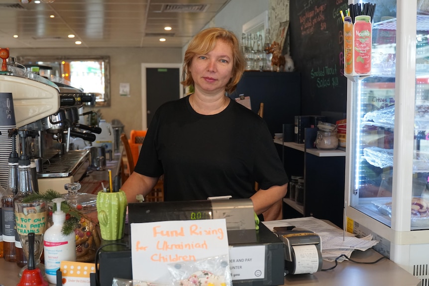 A woman wearing a black tshirt behind a cafe counter