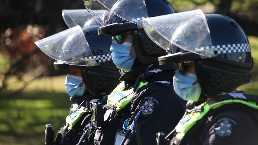 Three unidentifiable Victoria Police officers wearing face masks.