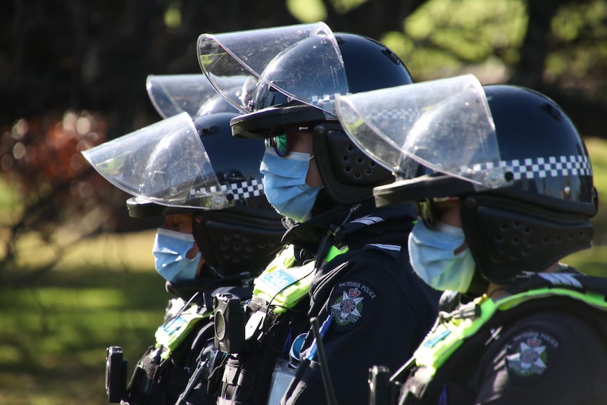 Three unidentifiable Victoria Police officers wearing face masks.