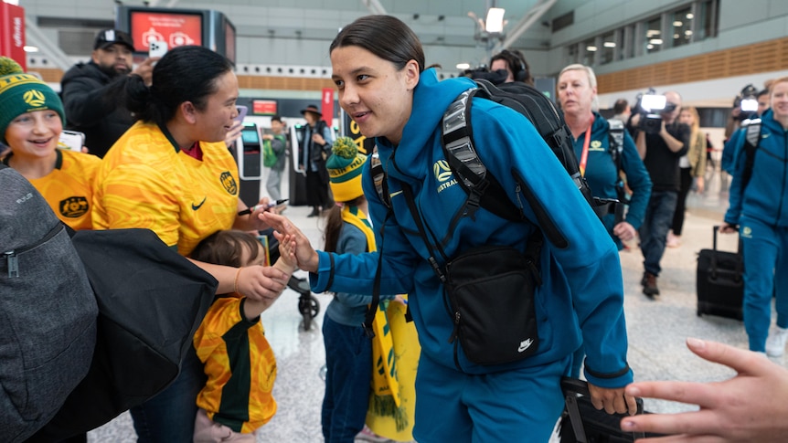 a female soccer player high fives a young fan at sydney airport