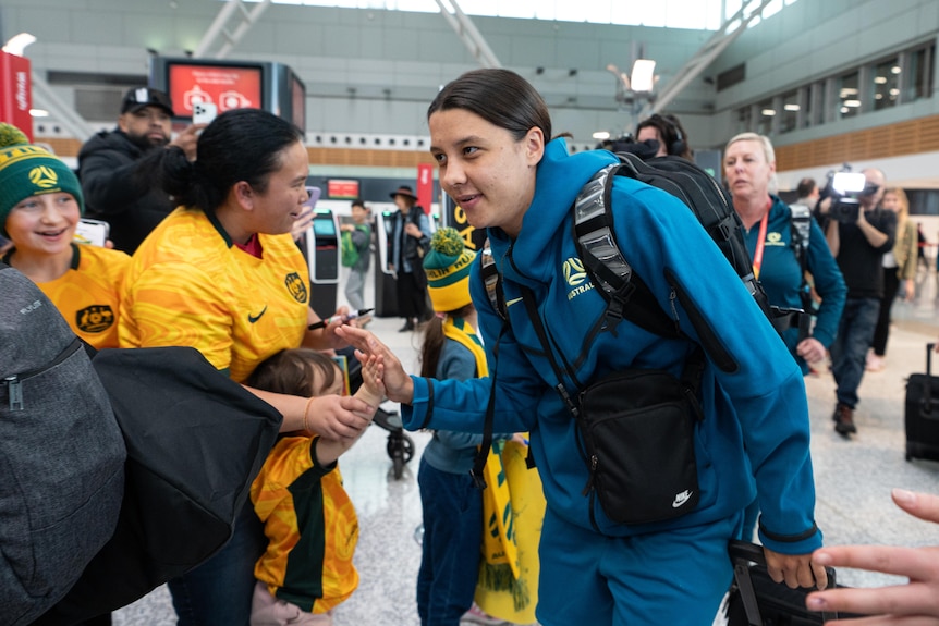 a female soccer player high fives a young fan at sydney airport