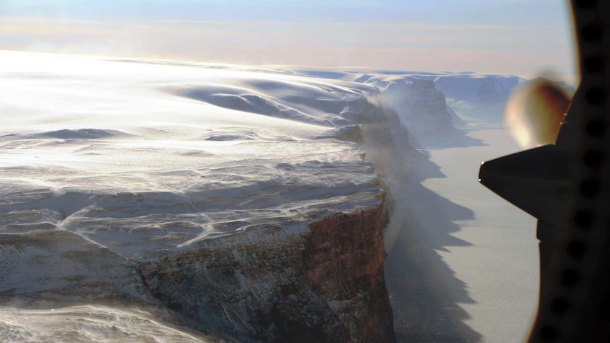 Petermann Glacier's east wall near the terminus of the floating ice shelf with blowing snow from the east