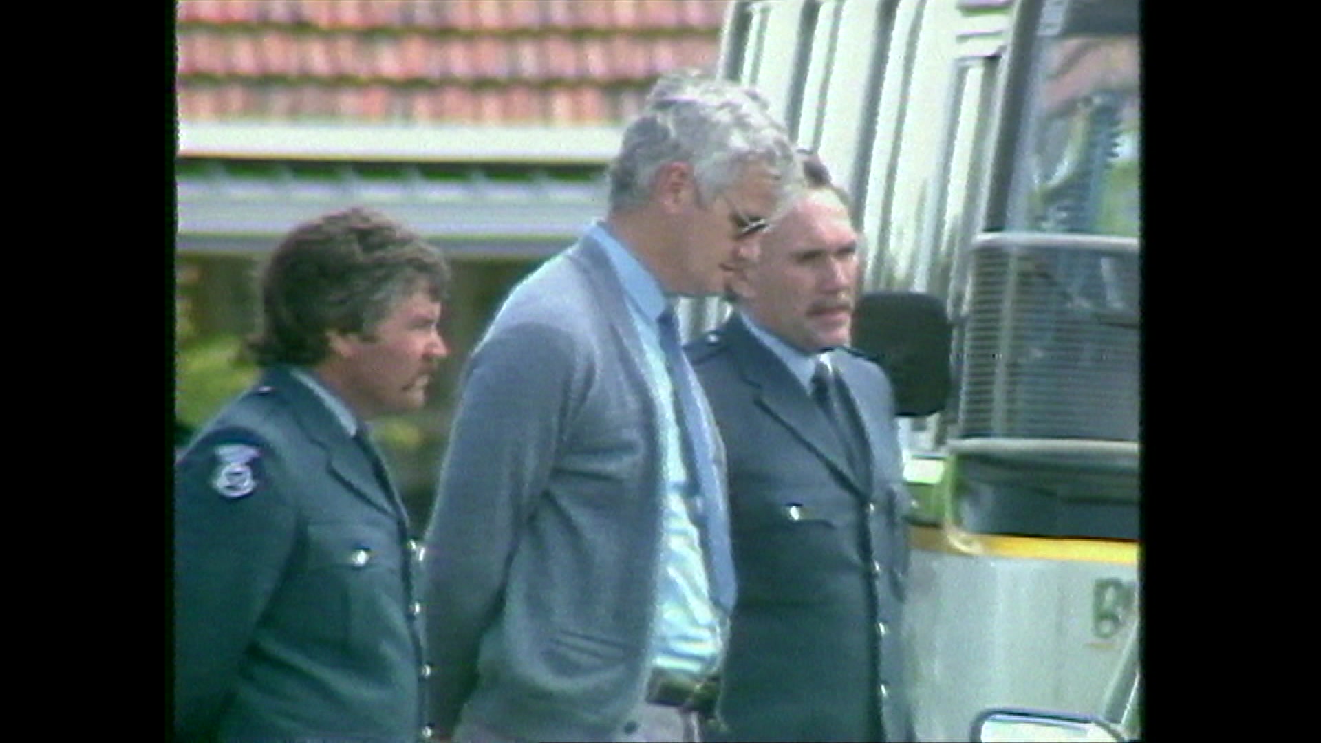 Man in the 1980s being moved into a police bus