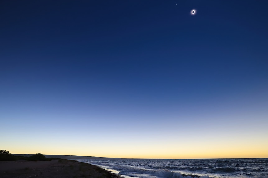 An isolated beach showcasing the solar eclipse