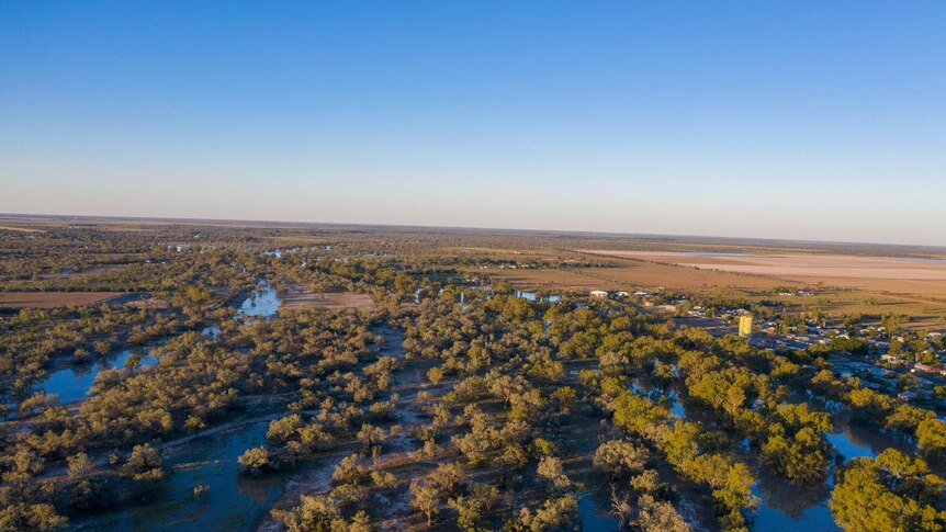 An aerial shot of a broad river area with trees and red dirt