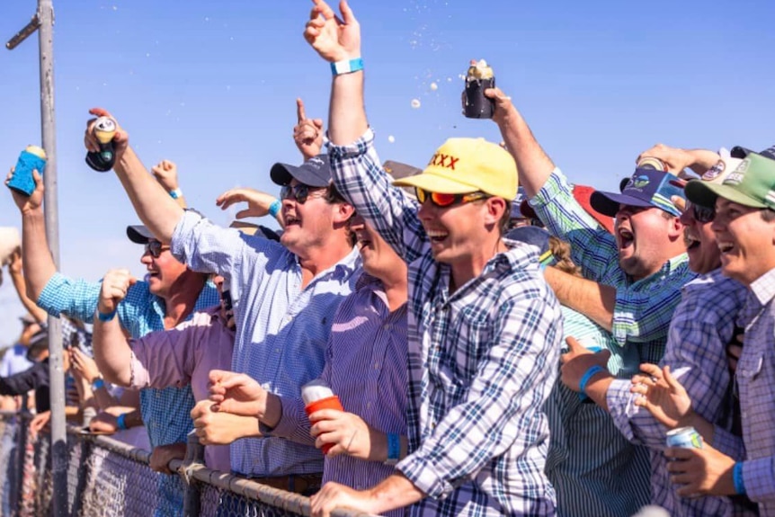 Crowd cheering at the rail of the race course