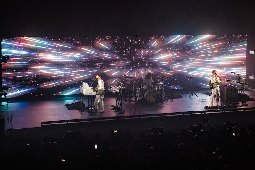 Air perform on Sydney Opera House stage with visuals of a ship in hyperspace behind them.