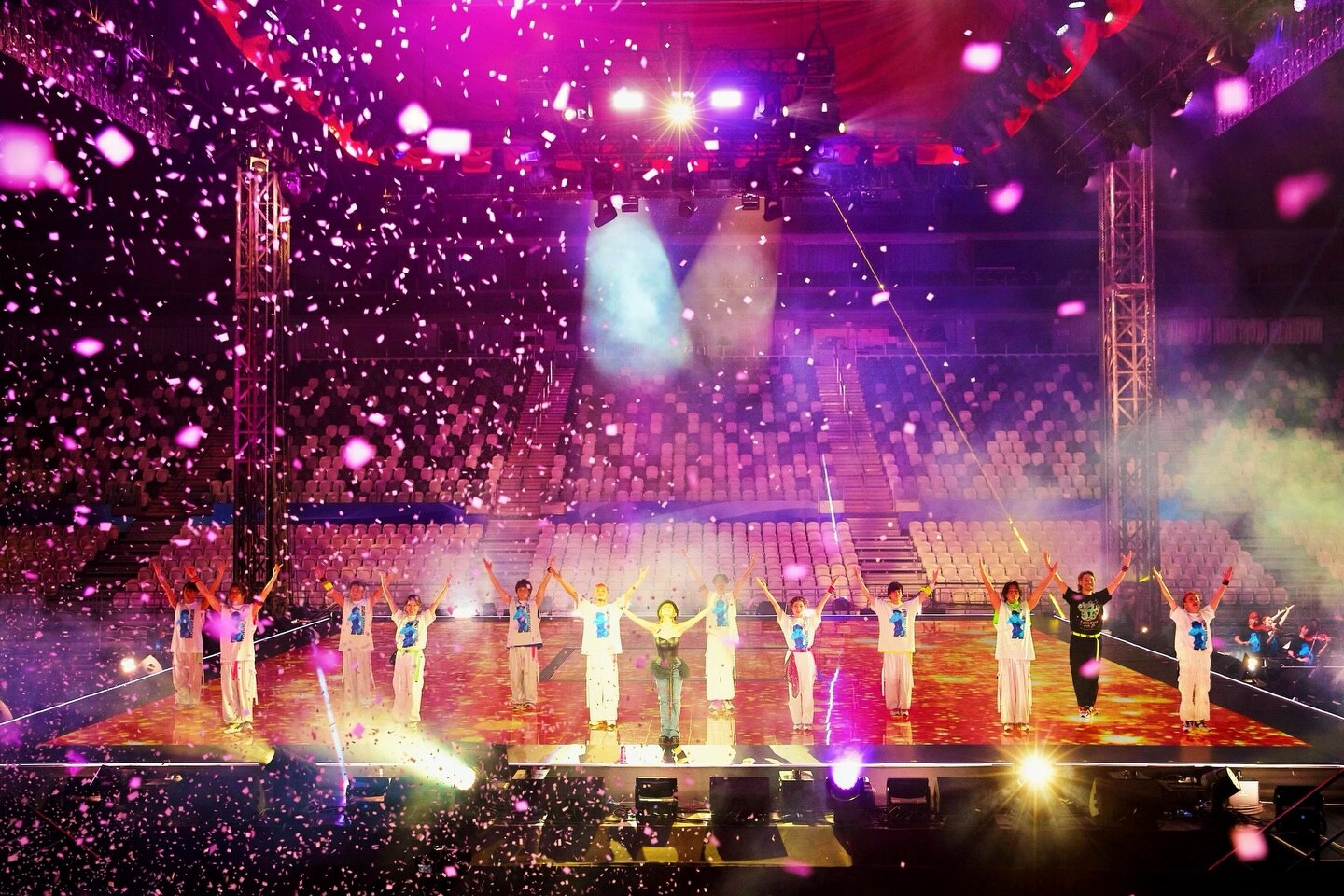 Ayumi Hamasaki and backup dancers perform under bright pink and yellow concert lights to an empty stadium.